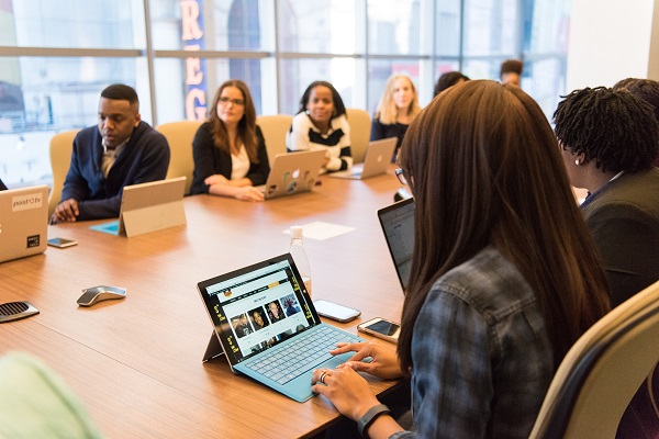 A group of people sitting around a table with laptops.