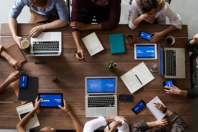 A group of people sitting around a table with laptops.